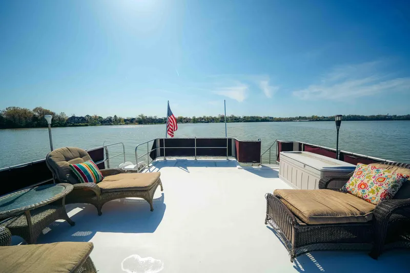 Slide: The Image of 1999 Sumerset houseboat deck with wicker furniture, colorful cushions, and scenic lake view. - 22