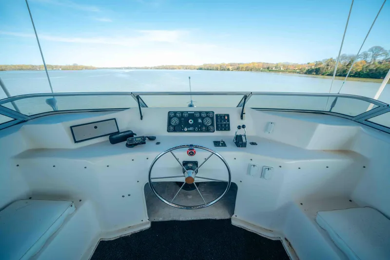 Slide: The Image of 1999 Sumerset houseboat helm with steering wheel and control panel, overlooking serene water. - 25