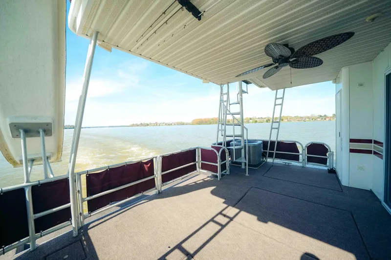Slide: The Image of 1999 Sumerset houseboat deck with ceiling fan, overlooking serene water and distant shoreline. - 4