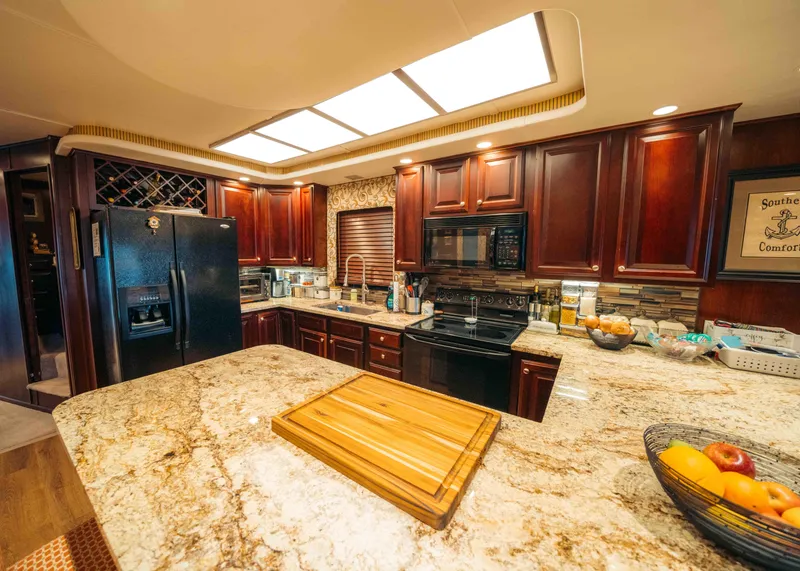 Slide: The Image of Luxurious kitchen in a 1999 Sumerset houseboat with granite countertops and wooden cabinetry. - 44