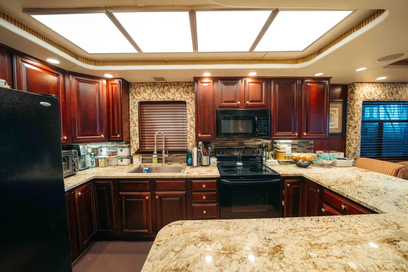Slide: The Image of Luxurious kitchen in a 1999 Sumerset houseboat with granite countertops and dark wood cabinets. - 46