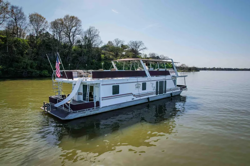 Slide: The Image of 1999 Sumerset houseboat with slide, ladder, and American flag on a sunny day. - 6