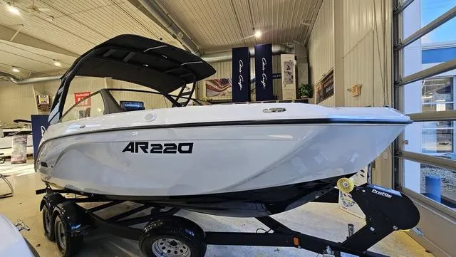 Slide: The Image of 2023 Yamaha Boats AR 220 displayed indoors on a trailer. - 2