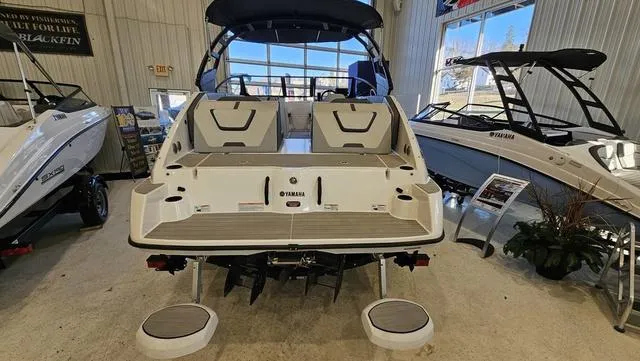 Slide: The Image of 2023 Yamaha Boats AR 220 displayed in showroom, rear view with seating and swim platform. - 5