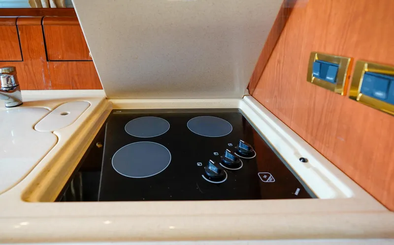 Slide: The Image of Stovetop in 2000 Sea Ray 510 Sundancer yacht kitchen, featuring four burners and wooden cabinetry. - 13