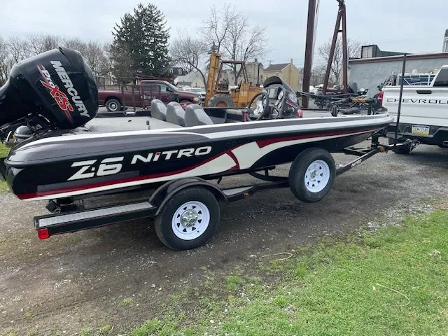 Slide: The Image of 2013 Nitro Z-6 boat on trailer, parked outdoors near vehicles and equipment. - 1