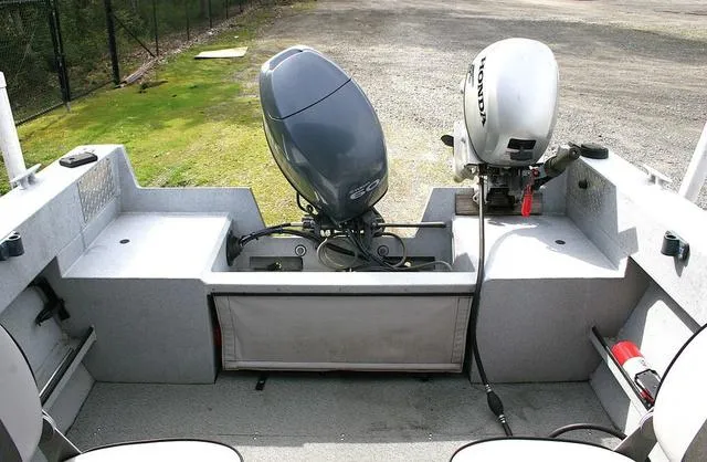 Slide: The Image of 2003 Hewescraft 160 Sportsman boat with dual outboard motors, parked on gravel. - 10