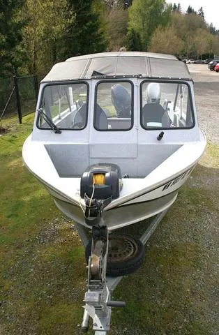 Slide: The Image of 2003 Hewescraft 160 Sportsman boat on trailer, parked on grassy area with trees in background. - 12