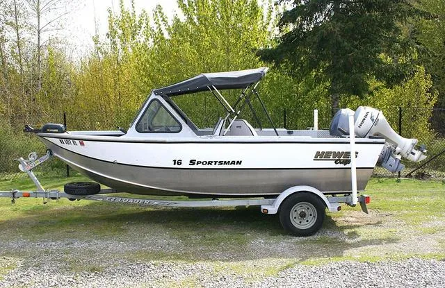 Slide: The Image of 2003 Hewescraft 160 Sportsman boat on trailer, parked outdoors with trees in background. - 2