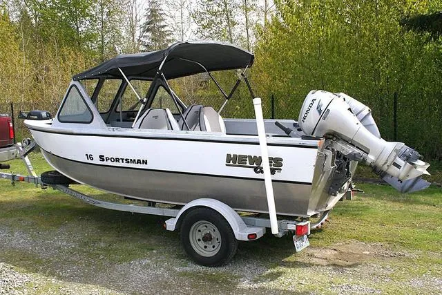 Slide: The Image of 2003 Hewescraft 160 Sportsman boat on trailer, parked on grass with trees in background. - 3