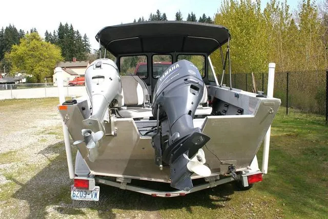 Slide: The Image of 2003 Hewescraft 160 Sportsman boat with dual outboard motors, parked outdoors. - 4