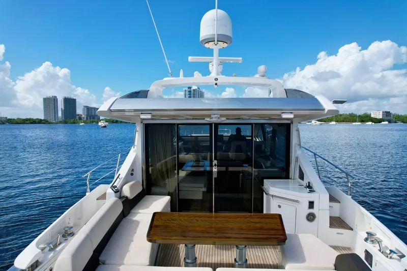 Slide: The Image of 2015 Azimut 55S yacht with spacious deck, wooden table, and scenic waterfront view. - 13