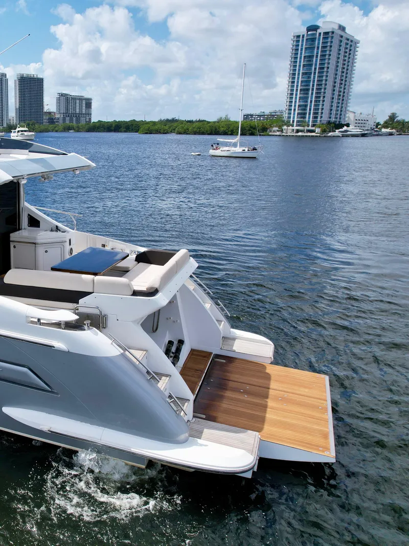 Slide: The Image of 2015 Azimut 55S yacht with open deck, docked on a sunny waterfront with cityscape. - 17