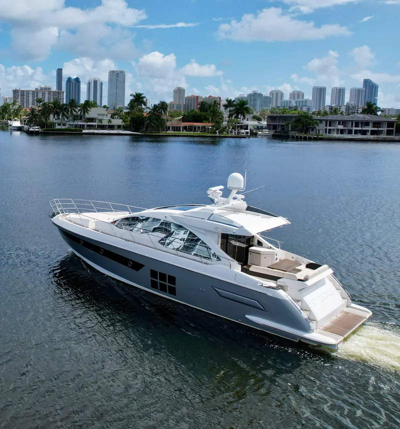 Slide: The Image of 2015 Azimut 55S yacht cruising on a serene waterway with city skyline backdrop. - 8