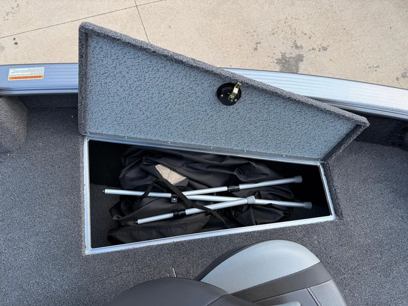 Slide: The Image of 2025 Lund 1875 Pro Guide boat storage compartment with folded equipment inside. - 12