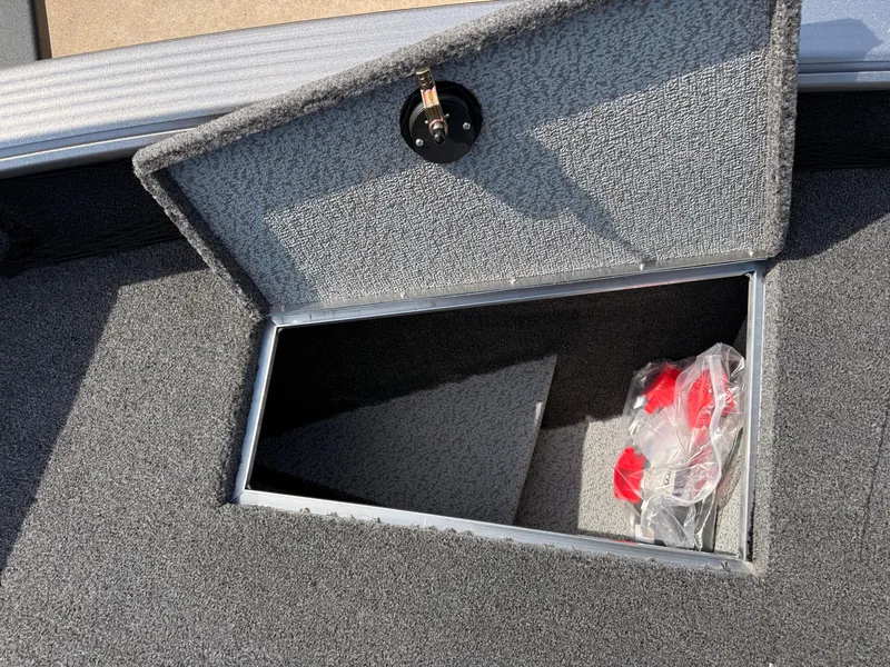 Slide: The Image of 2025 Lund 1875 Pro Guide boat storage compartment with open lid and red accessories inside. - 14