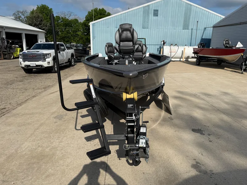 Slide: The Image of 2025 Lund 1875 Pro Guide boat on trailer, parked outdoors near industrial buildings. - 2