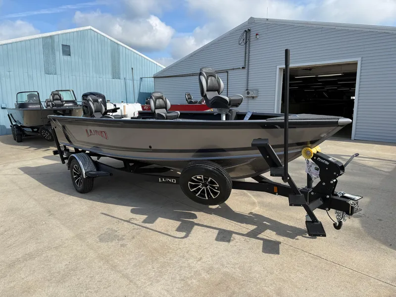 Slide: The Image of 2025 Lund 1875 Pro Guide fishing boat on trailer, parked outside a warehouse. - 3