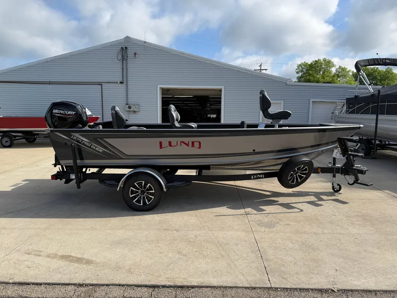 Slide: The Image of 2025 Lund 1875 Pro Guide fishing boat on trailer, parked outside a building. - 4