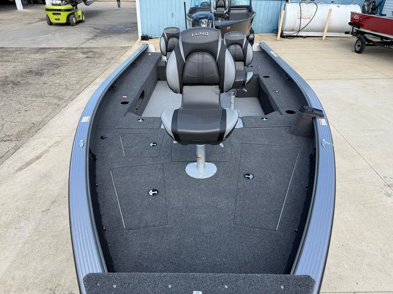 Slide: The Image of 2025 Lund 1875 Pro Guide fishing boat with seating, docked outdoors. - 9
