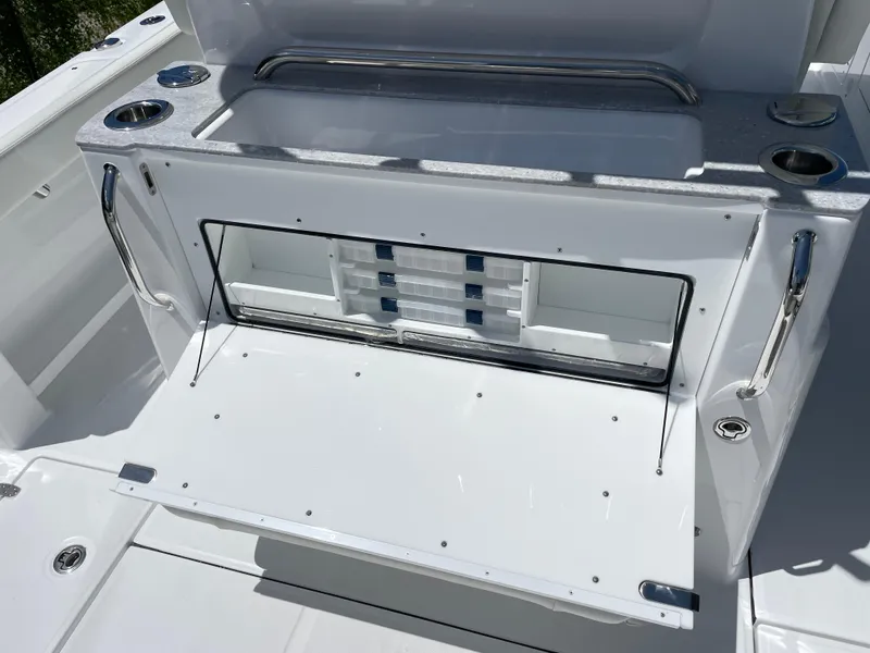 Slide: The Image of 2025 Everglades 315 Center Console boat storage compartment with open hatch and cup holders. - 47