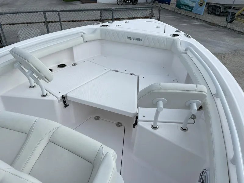 Slide: The Image of 2023 Everglades 235CC boat interior with white seating and deck, docked in a marina. - 12