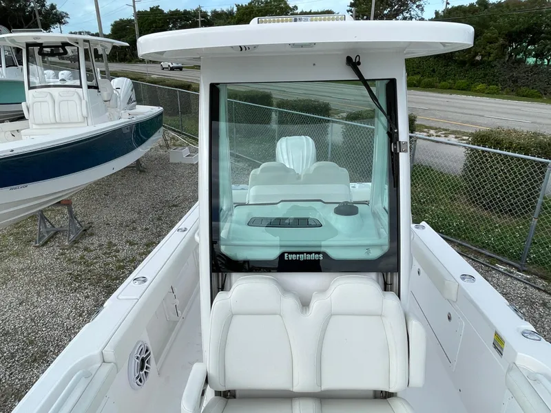 Slide: The Image of 2023 Everglades 235CC boat with white seating and console, parked outdoors. - 15