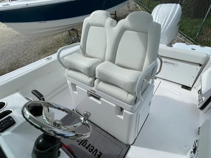 Slide: The Image of 2023 Everglades 235CC boat interior with dual white captain's chairs and steering wheel. - 22
