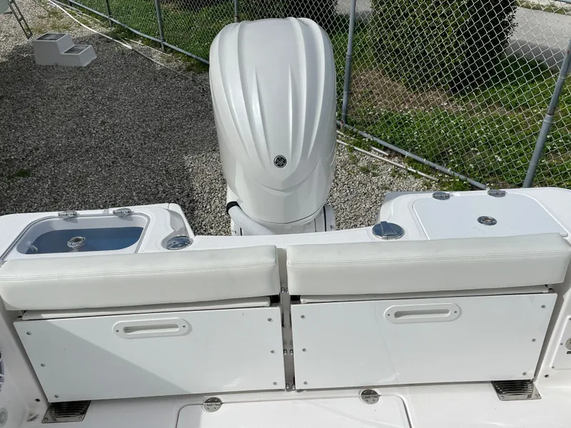 Slide: The Image of 2023 Everglades 235CC boat with white seating and engine, parked near a chain-link fence. - 28