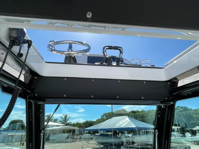 Slide: The Image of 2023 Everglades 273CC boat helm view with clear sky and marina background. - 16