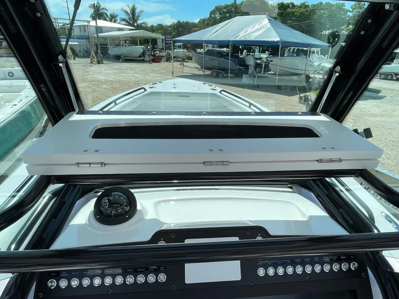 Slide: The Image of 2023 Everglades 273CC boat dashboard with compass and control panel, docked under a canopy. - 17