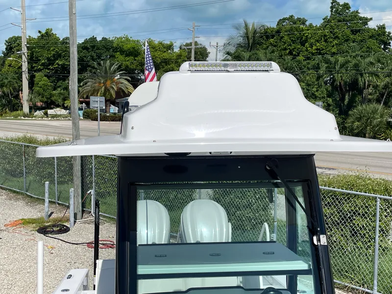 Slide: The Image of 2023 Everglades 273CC boat with T-top, parked outdoors, American flag in background. - 7