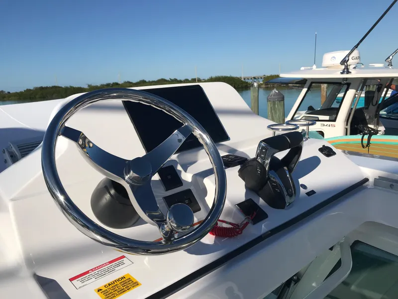 Slide: The Image of 2023 Everglades 273CC boat helm with steering wheel and controls, docked by the water. - 9