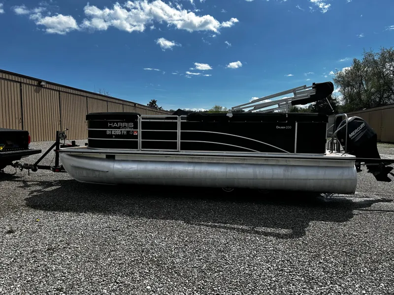 Slide: The Image of 2014 Harris FloteBote 200 Cruiser CS pontoon boat on gravel lot under blue sky. - 2