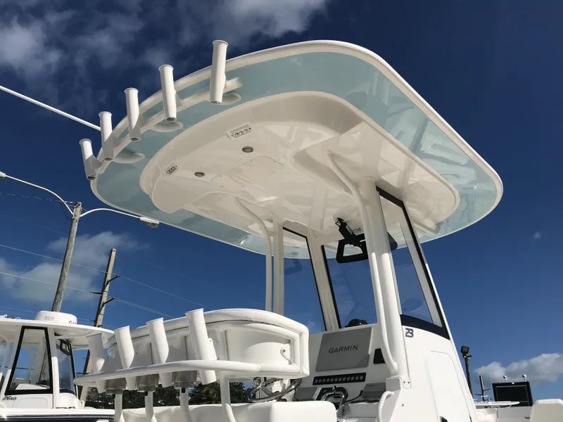 Slide: The Image of 2023 Regulator 23 boat with T-top and rod holders under a clear blue sky. - 26