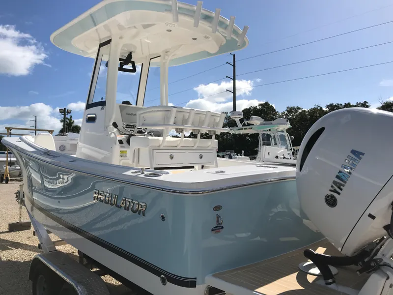 Slide: The Image of 2023 Regulator 23 boat with Yamaha engine, light blue hull, and T-top, parked outdoors. - 28