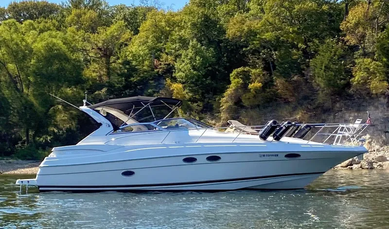 Slide: The Image of 2006 Regal Commodore 3560 IB yacht cruising on a scenic lake with lush green trees. - 1