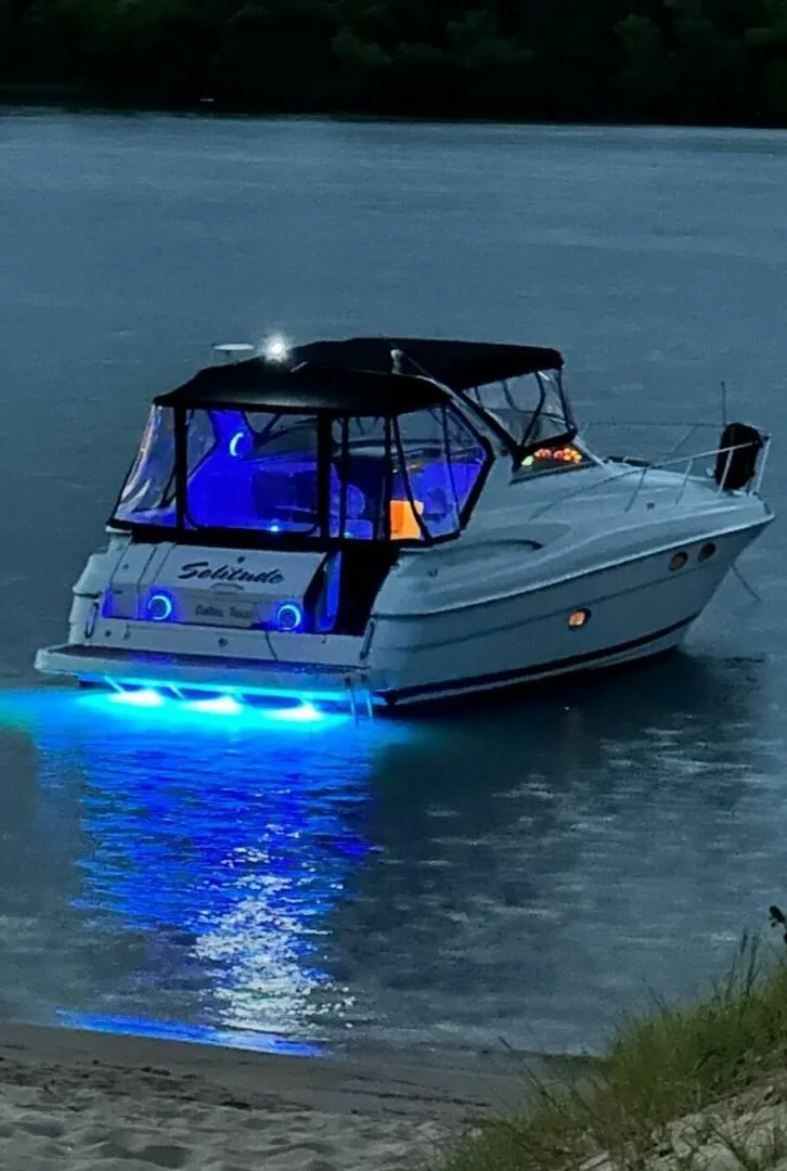 Slide: The Image of 2006 Regal Commodore 3560 IB boat with blue LED lights on water at dusk. - 36