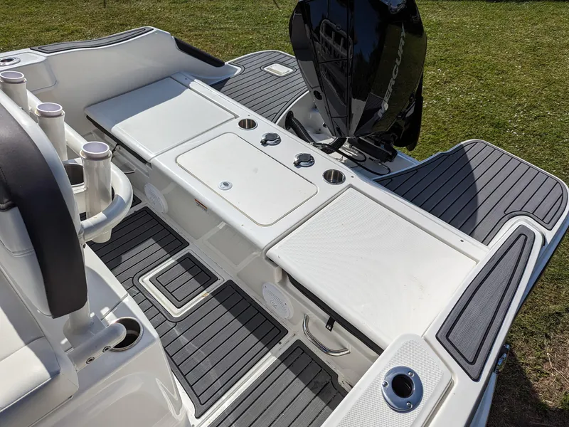 Slide: The Image of 2025 Bayliner Trophy T22CC boat deck with seating, storage, and motor, on grassy background. - 7
