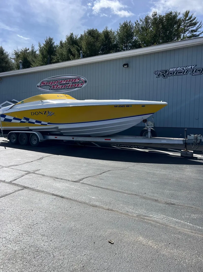 The Image of 1998 Donzi 33ZX speedboat in yellow on trailer, parked outside a building. - 1