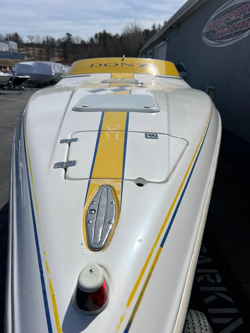 Slide: The Image of 1998 Donzi 33ZX boat with yellow and blue stripes, parked outdoors. - 8