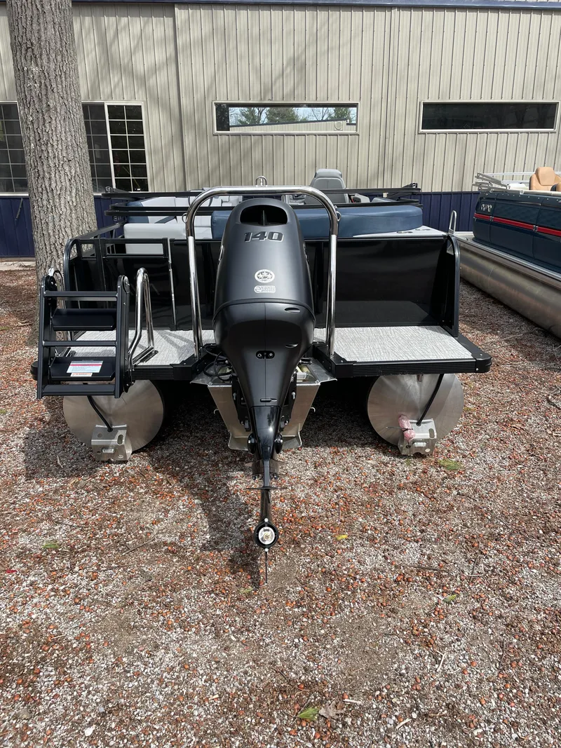 Slide: The Image of 2025 Avalon 25 LSZ ELITE pontoon boat with powerful outboard motor, parked on gravel. - 10