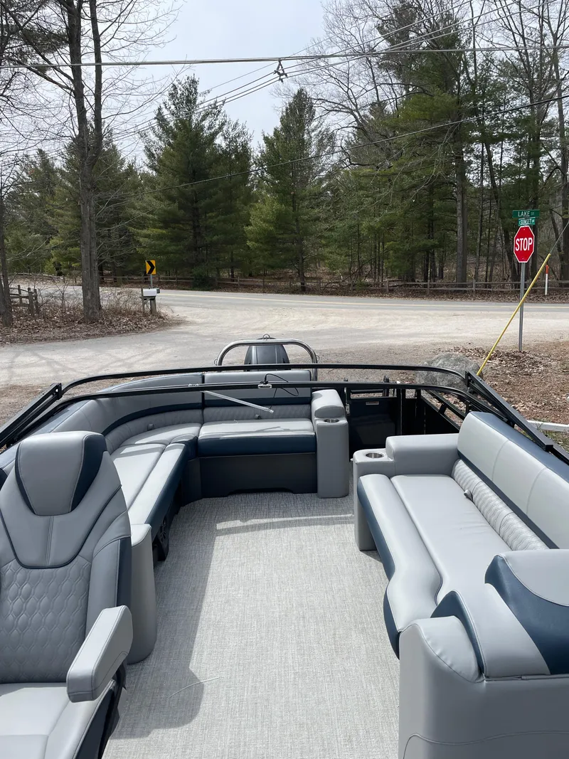 Slide: The Image of 2025 Avalon 25 LSZ ELITE pontoon boat with luxurious seating, parked near a wooded road. - 4