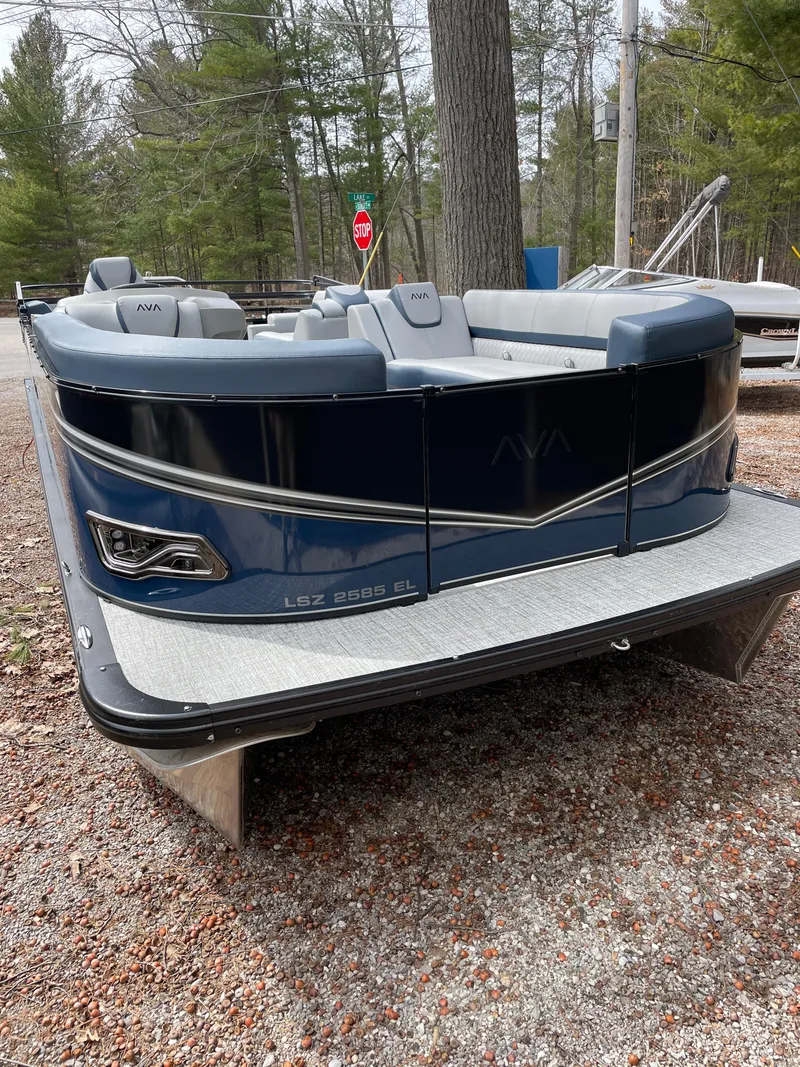 Slide: The Image of 2025 Avalon 25 LSZ Elite pontoon boat with sleek design, parked on gravel. - 7