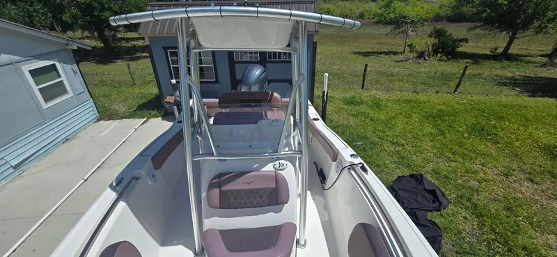 Slide: The Image of 2017 Tidewater 210 LXF boat with T-top, parked near a house and grassy area. - 9