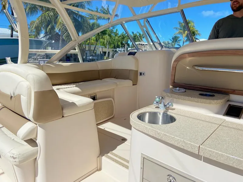 Slide: The Image of 2013 Grady-White Freedom 335 boat interior with seating and kitchenette under clear blue sky. - 5