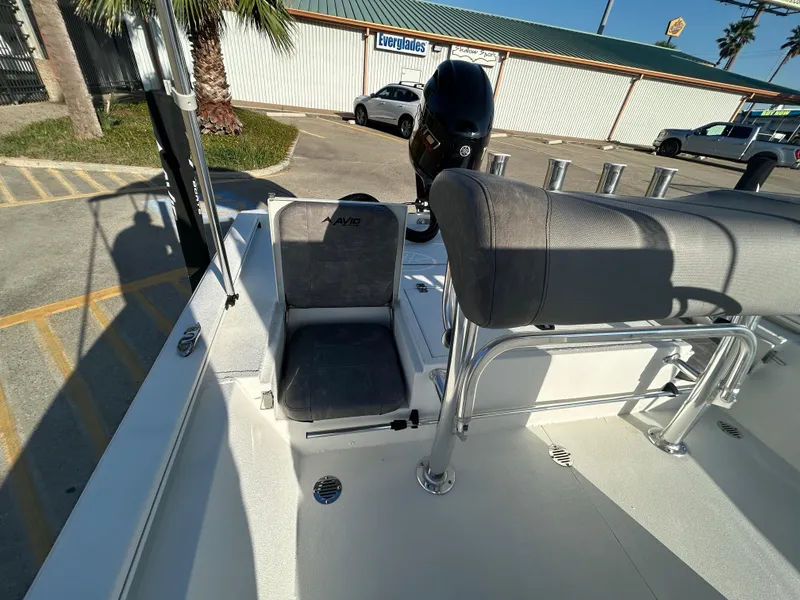 Slide: The Image of 2025 Avid 19 FSX boat interior with seating and motor, parked outdoors. - 14
