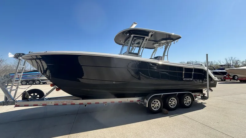 Slide: The Image of 2021 Robalo R302 Center Console boat on a trailer under clear blue sky. - 3