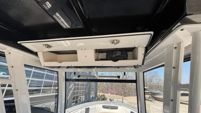 Slide: The Image of 2021 Robalo R302 Center Console interior with overhead storage and radio equipment. - 38