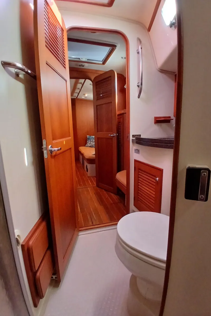 Slide: The Image of 2006 Island Packet 440 yacht interior, featuring a compact bathroom with wooden accents. - 23